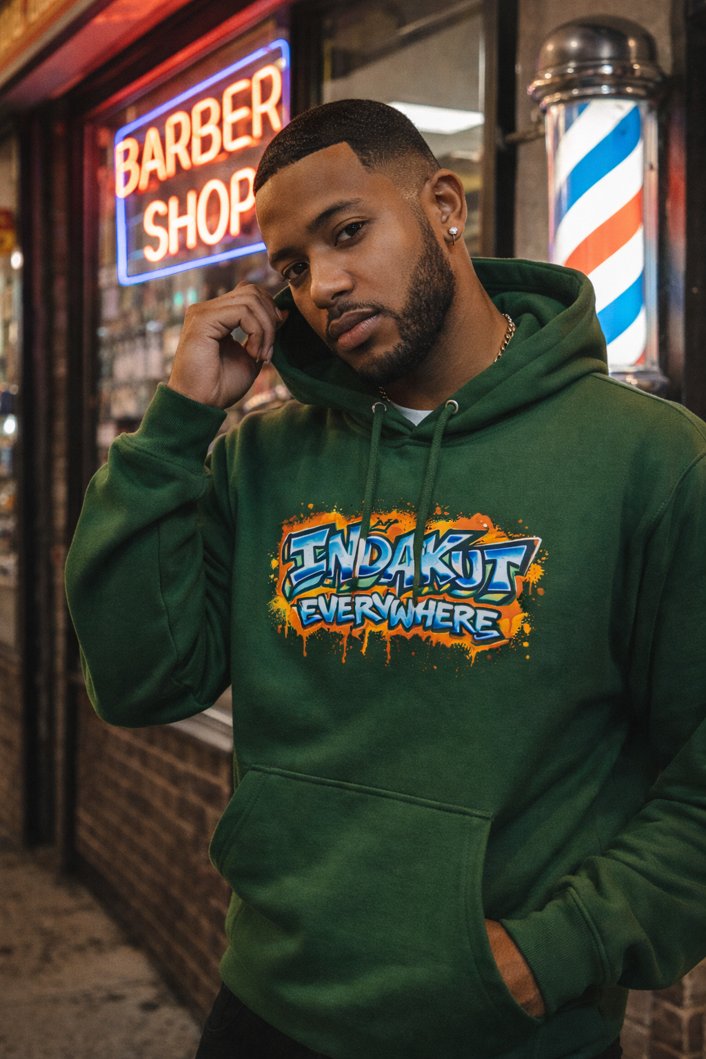 Indakut Everywhere green hoodie with graffiti logo styled in urban streetwear setting