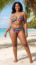 Indakut Everywhere string bikini bottom with graffiti all over print worn on tropical beach in women’s swimwear setting